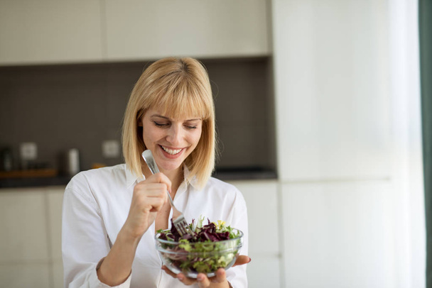 Pregnant woman holding glass bowl with fresh salad - Foto, Imagen