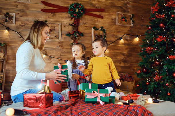 Mother and children with gifts in the house for Christmas - 写真・画像