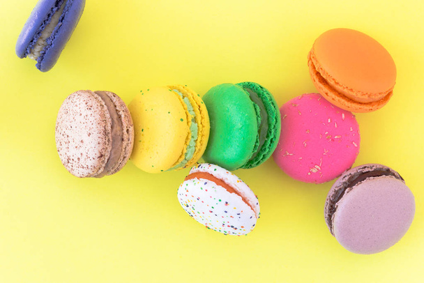 Sweet colorful French macaroon biscuits on pastel yellow background - Photo, Image