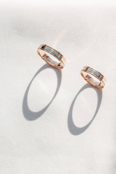 2つの金のリングを持つロマンチックな結婚指輪の背景、光輝く背景の垂直バランス、招待状やグリーティングカードのためのコピースペース - 写真・画像