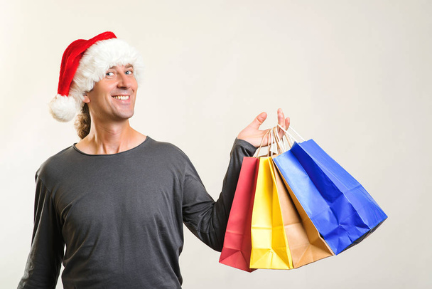 Weihnachtseinkauf. Saisonverkäufe, Rabatte und Angebote. Glücklicher Mann hält Papiertüten in der Hand.  - Foto, Bild