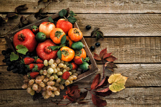 Autumn crop fruits. Autumn background with fall leaves, red apples and grapes. Fall harvest on aged wood with copy space. Mockup for seasonal offers, top view. Vintage style. - Photo, image