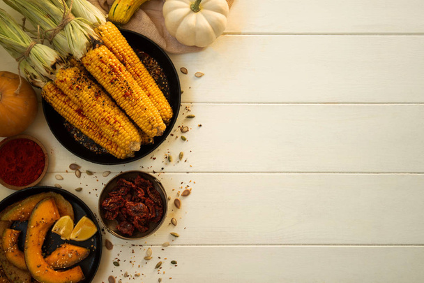 Delicious golden grilled corn on the cob, baked pumpkins, salt and seeds served barbecue grill on the wooden vintage board with a spice and fresh farm vegetables. Organic, bio food. - Fotografie, Obrázek