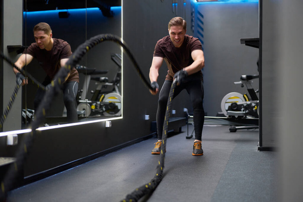 Athlete man in training with ropes near mirror. - Valokuva, kuva