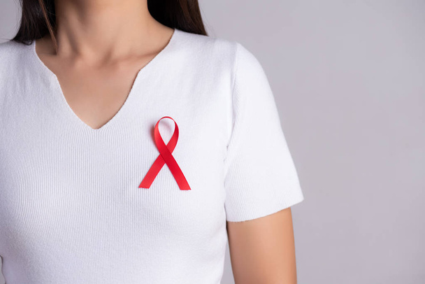 Close-up van rode badge lint op de borst van de vrouw ter ondersteuning van AIDS Day. Gezondheidszorg, geneeskunde en aids-bewustzijn. - Foto, afbeelding