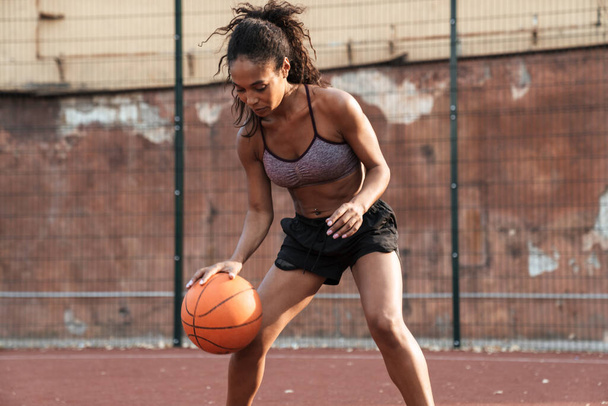 Image of concentrated african american woman playing basketball  - Fotoğraf, Görsel