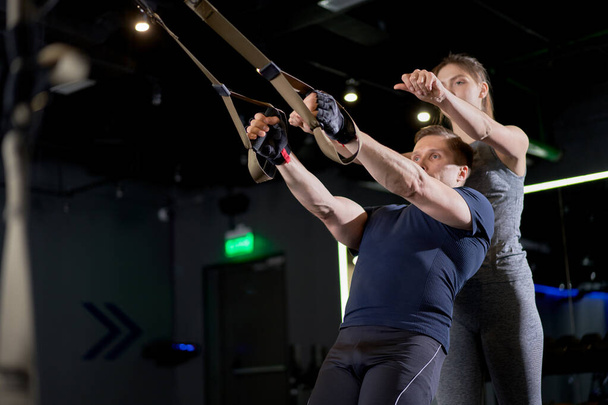 athletischer Mann im Training mit Gummibändern mit Frauentrainerin - Foto, Bild