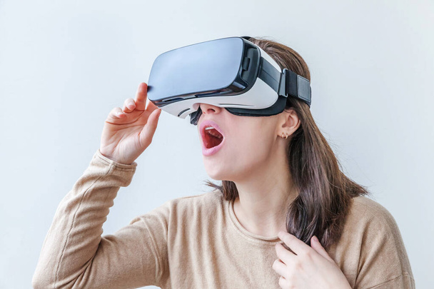 Smile young woman wearing using virtual reality VR glasses helmet headset on white background. Smartphone using with virtual reality goggles. Technology, simulation, hi-tech, videogame concept - Photo, image