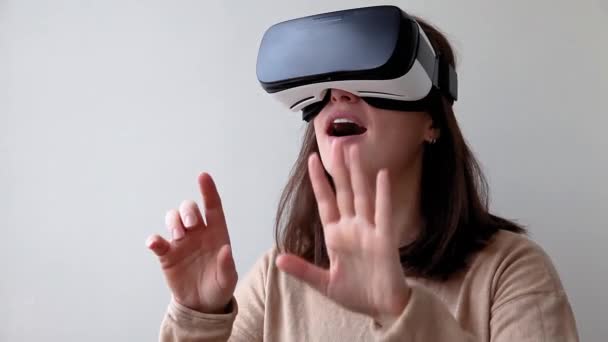 Sonríe mujer joven usando realidad virtual gafas VR casco auriculares sobre fondo blanco. Smartphone con gafas de realidad virtual. Tecnología, simulación, alta tecnología, concepto de videojuego - Imágenes, Vídeo