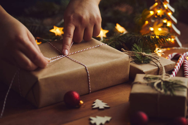 Woman packing Christmas gift in paper on table - Φωτογραφία, εικόνα