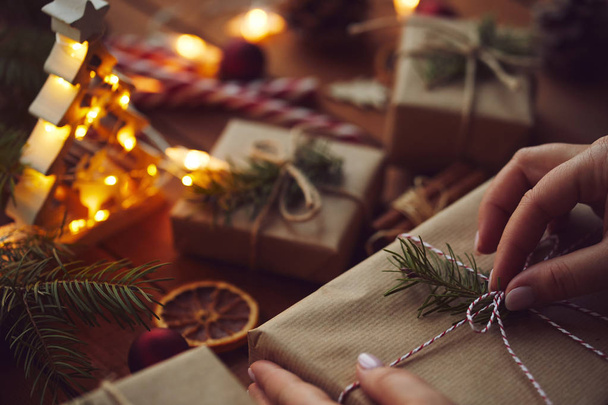 Woman wrapping Christmas gift in paper on table - Foto, afbeelding