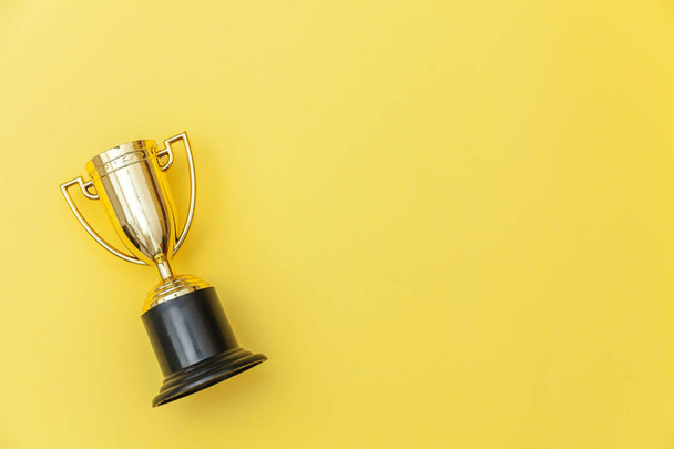 Simply flat lay design winner or champion gold trophy cup isolated on yellow colorful background. Victory first place of competition. Winning or success concept. Top view copy space - Photo, Image