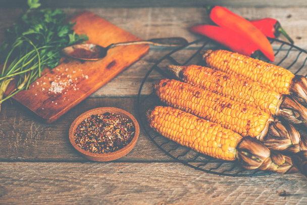 Corn grilled with cheese and spices on the dark rustic background. Autumn food background. Fast food in the summer or fall. Toned image. - Valokuva, kuva