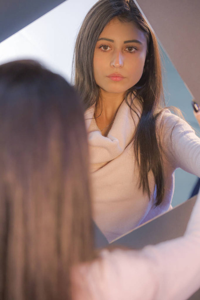 piękne młody kobieta brunetka model spójrz jej sam w w lustro - Zdjęcie, obraz