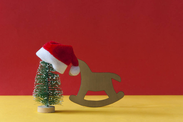 Santa Claus hat and Christmas tree on colorful paper background - Photo, Image