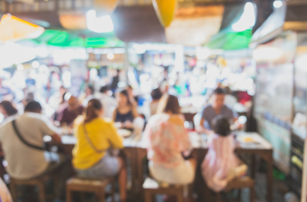 Image floue abstraite de personnes assises autour de la table dans un magasin asiatique local de nourriture de rue sur le marché frais
. - Photo, image
