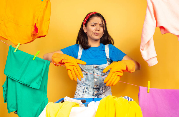 Funny and beautiful housewife doing housework on yellow background - Fotó, kép