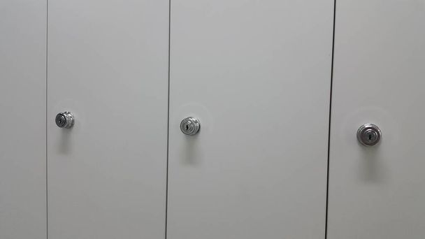 Перспективный вид шкафчиков или шкафов в ряд с белыми дверями
 - Фото, изображение