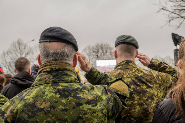 Soldados del ejército canadiense se paran y observan el desfile. Militar en camuflaje. Ropa de guerrero. Otoño. Es un día desagradable.
. - Foto, Imagen