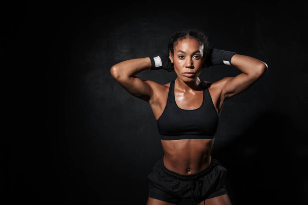 Imagen de una fuerte mujer afroamericana de pie en envolturas de mano de boxeo
 - Foto, Imagen