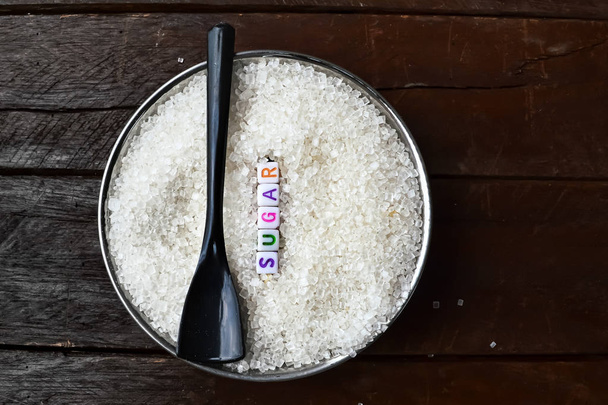 sugar text writing and black spoon on sugar,black background on  - Photo, Image