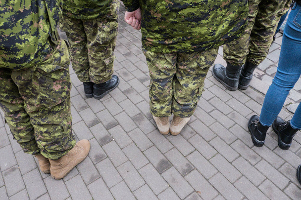 Soldados del ejército canadiense se paran y observan el desfile. Militar en camuflaje. Ropa de guerrero. Otoño. Es un día desagradable.
. - Foto, imagen