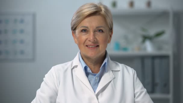 Professional female doctor in uniform smiling on camera, medical occupation - Imágenes, Vídeo