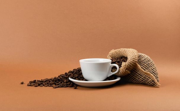 Taza de café caliente y granos de café en bolsa de arpillera
 - Foto, imagen
