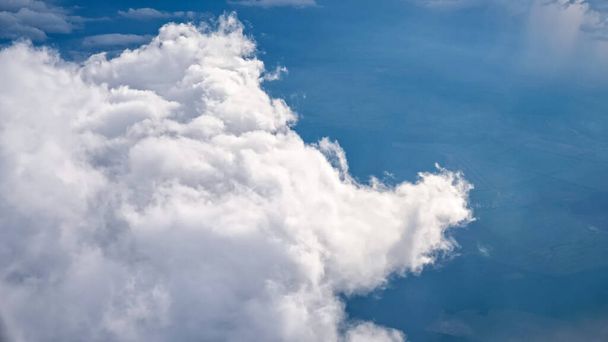 weiße weiche, flauschige Wolken über der grünen Landschaft, Luftaufnahme aus dem Flugzeug. - Foto, Bild