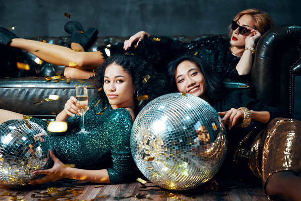 Pretty multiethnic young women relaxed after party, lying down on the floor and sofa - 写真・画像