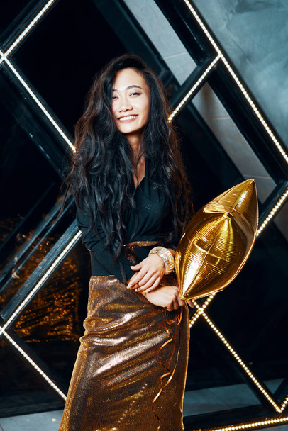 Pretty happy Asian woman having fun and dancing at party holding golden balloon - Foto, Imagem