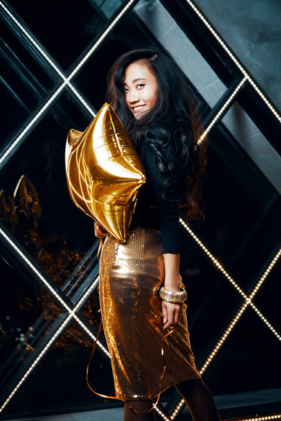 Pretty happy Asian woman having fun and dancing at party holding golden balloon - Fotoğraf, Görsel