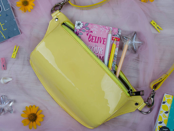 accessori in pelle verniciata gialla per donne e fiori su sfondo rosa
 - Foto, immagini