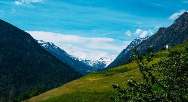 Beautiful view of idyllic Swiss alpine mountains scenery with meadows and snow capped mountain peaks on a beautiful sunny day with blue sky in springtime. Beauty world. - Photo, image