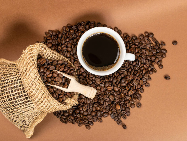 Ζεστό φλιτζάνι καφέ και κόκκους καφέ σε τσάντα λινάτσα - Φωτογραφία, εικόνα