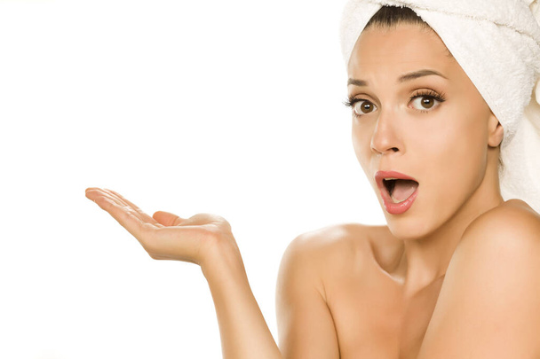 Young excited advertizing woman with towel on her head on white background - Foto, Imagen