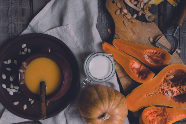 Bowl of pumpkin organic soup with cream and pumpkin seeds on gray background. Dietary vegetarian food. Concept of healthy eating food. Homemade autumn soup. Top view with copy space. Toned image. - Foto, imagen