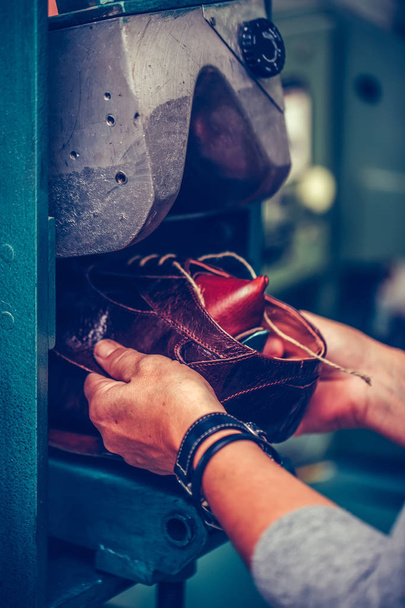 Experienced shoemaker using a special machine for putting shoes  - 写真・画像