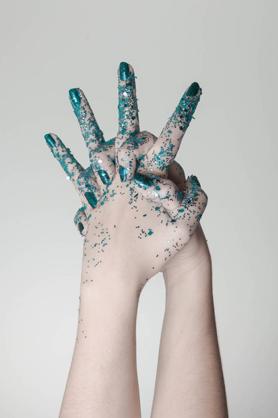 Beautiful woman hands with blue glitter in front of black, can be used as background - Fotó, kép