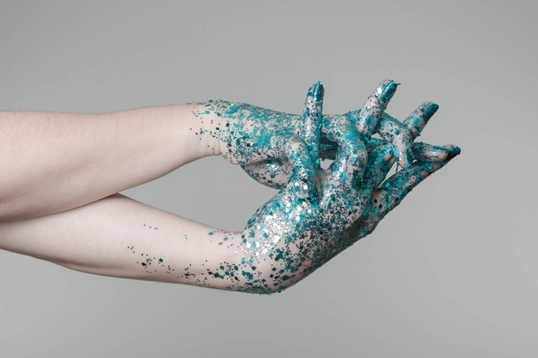 Beautiful woman hands with blue glitter in front of black, can be used as background - Foto, Bild