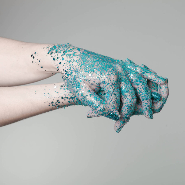 Beautiful woman hands with blue glitter in front of black, can be used as background - Fotoğraf, Görsel