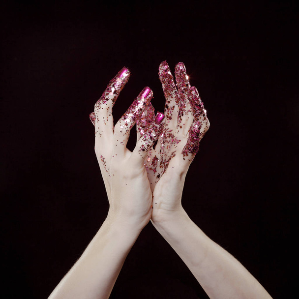 beautiful woman hands with pink glitter in front of black background - Фото, изображение