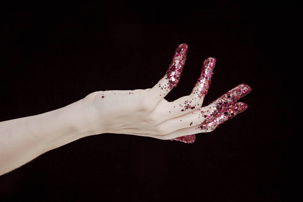 beautiful woman hands with pink glitter in front of black background - Foto, afbeelding