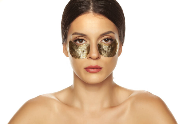junge schöne Frau posiert mit goldenen Flecken unter ihren Augen  - Foto, Bild