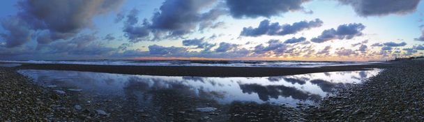 Impresionante paisaje marino panorámico al atardecer en la playa de grava con arena
 - Foto, Imagen