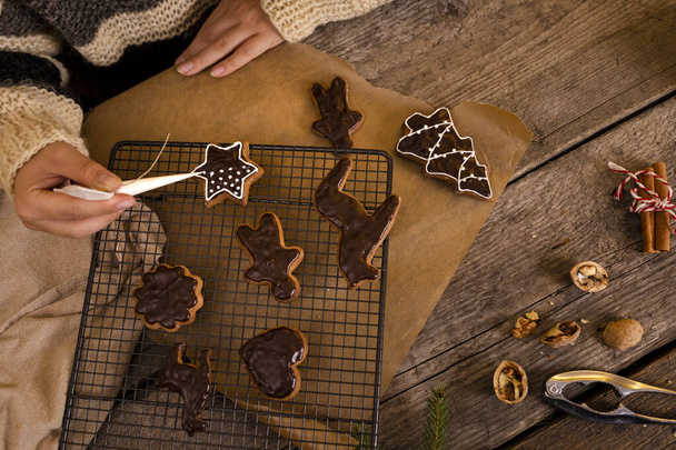 woman decorates homemade gingerbreads with icing. - Photo, Image