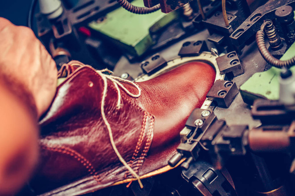 Опытный сапожник с помощью специальной машины для пошива обуви
  - Фото, изображение