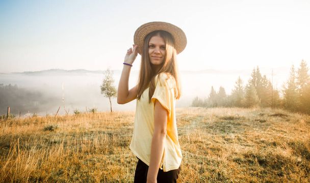 Молода безтурботна жінка насолоджується природою і сонячним світлом у солом'яному капелюсі
 - Фото, зображення