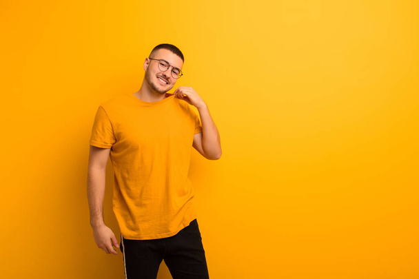 young handsome man laughing cheerfully and confidently with a casual, happy, friendly smile against flat background - Photo, Image