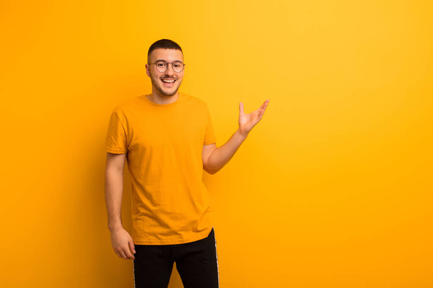 young handsome man feeling happy, surprised and cheerful, smiling with positive attitude, realizing a solution or idea against flat background - Foto, immagini